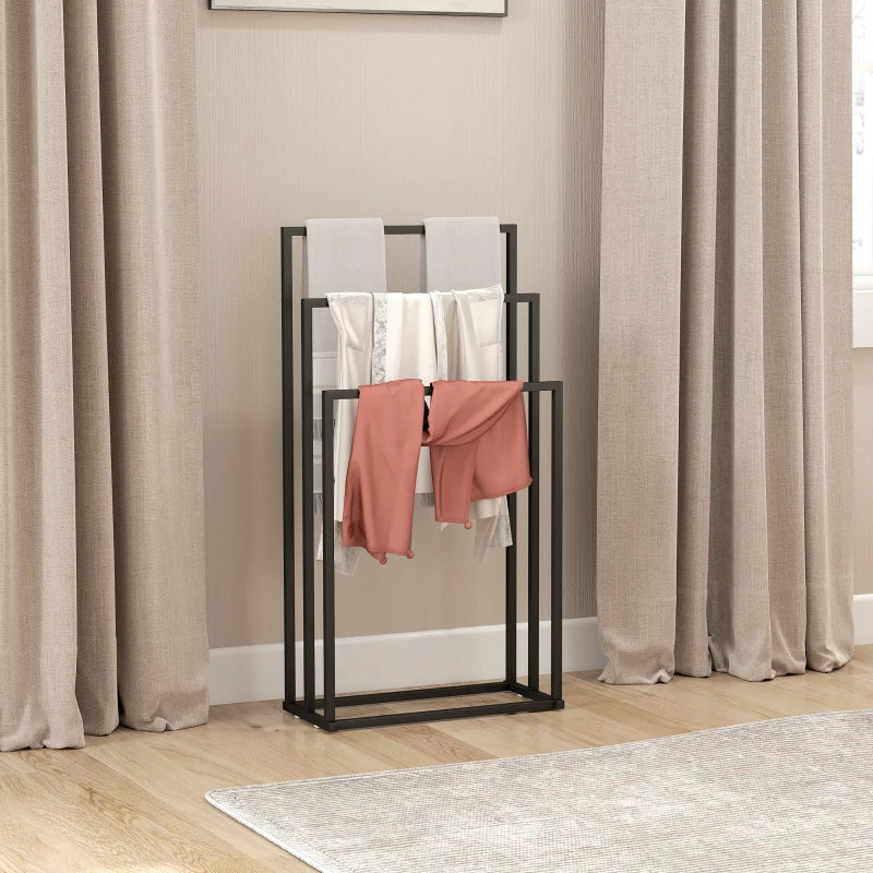 Black open-frame freestanding towel rack with three bars and hanging pink towels.