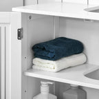 White under sink cabinet open shelf with folded towels and toiletry bottles