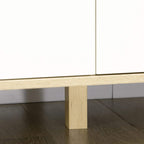 Close-up of light brown wooden leg and white drawer bottom on 6-drawer dresser
