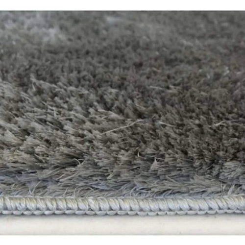 Close-up of grey shaggy rug pile with braided edge trim.