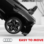 Black kids electric ride-on car front wheel with auxiliary wheels, side view close-up