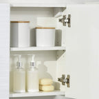 White bathroom cabinet interior with bottles, bar soap, and adjustable shelf compartments