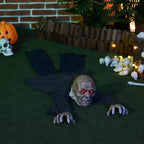 Crawling zombie Halloween decoration on grass, glowing red eyes and outstretched hands