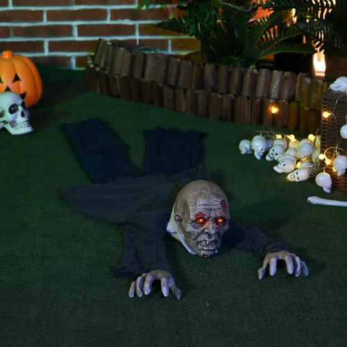 Crawling zombie Halloween decoration on grass, glowing red eyes and outstretched hands