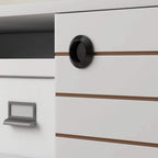 White cabinet door detail with round black handle on a striped TV storage unit.