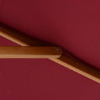 Wine red parasol fabric underside with wooden support beam and fastening bolt.
