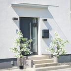 Pair of artificial honeysuckle plants in black pots with white flowers on outdoor steps