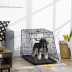 Black wire dog travel crate with top handle and dark base tray, holding a dog