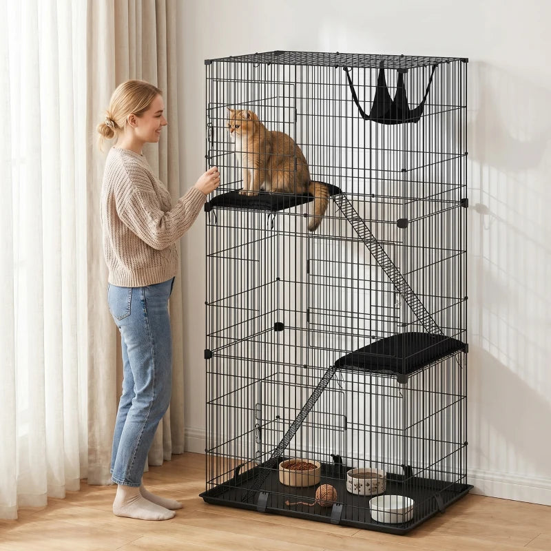 Black 3-tier cat cage with hammock and lower tray, kitten relaxing inside