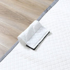 Close-up of white quilted mattress pad folded on a gray folding bed base edge