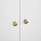White cabinet doors with brass round knobs and geometric panel detailing