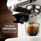 Close-up of steam wand pouring espresso into a glass cup on white machine