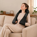 Black neck and shoulder massager wrap with side controller, worn on a seated woman