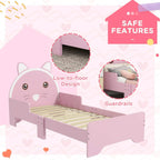 Pink toddler bed frame with cat-themed headboard and guardrails, low-to-floor design.