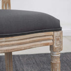 Grey upholstered dining chair side with thick cushion and distressed wood frame