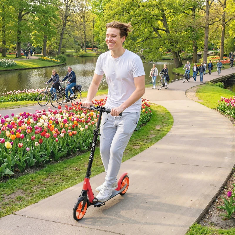 Red and black folding kick scooter with orange wheels standing on paved path