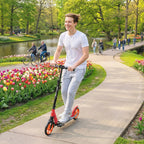 Red and black folding kick scooter with orange wheels standing on paved path