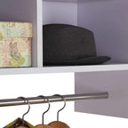 Close-up of metal hanging rail with coat hangers under a white storage shelf