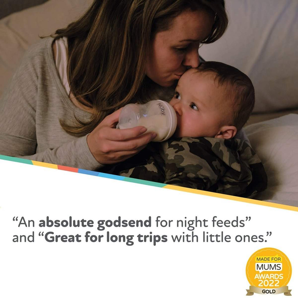 Baby drinking from Nuby bottle while held by a parent on a couch
