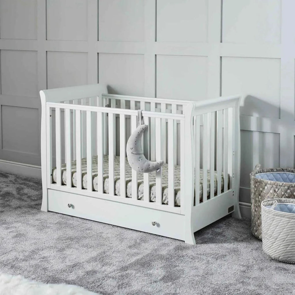 White mini cot bed with slatted sides and storage drawer, set with mattress