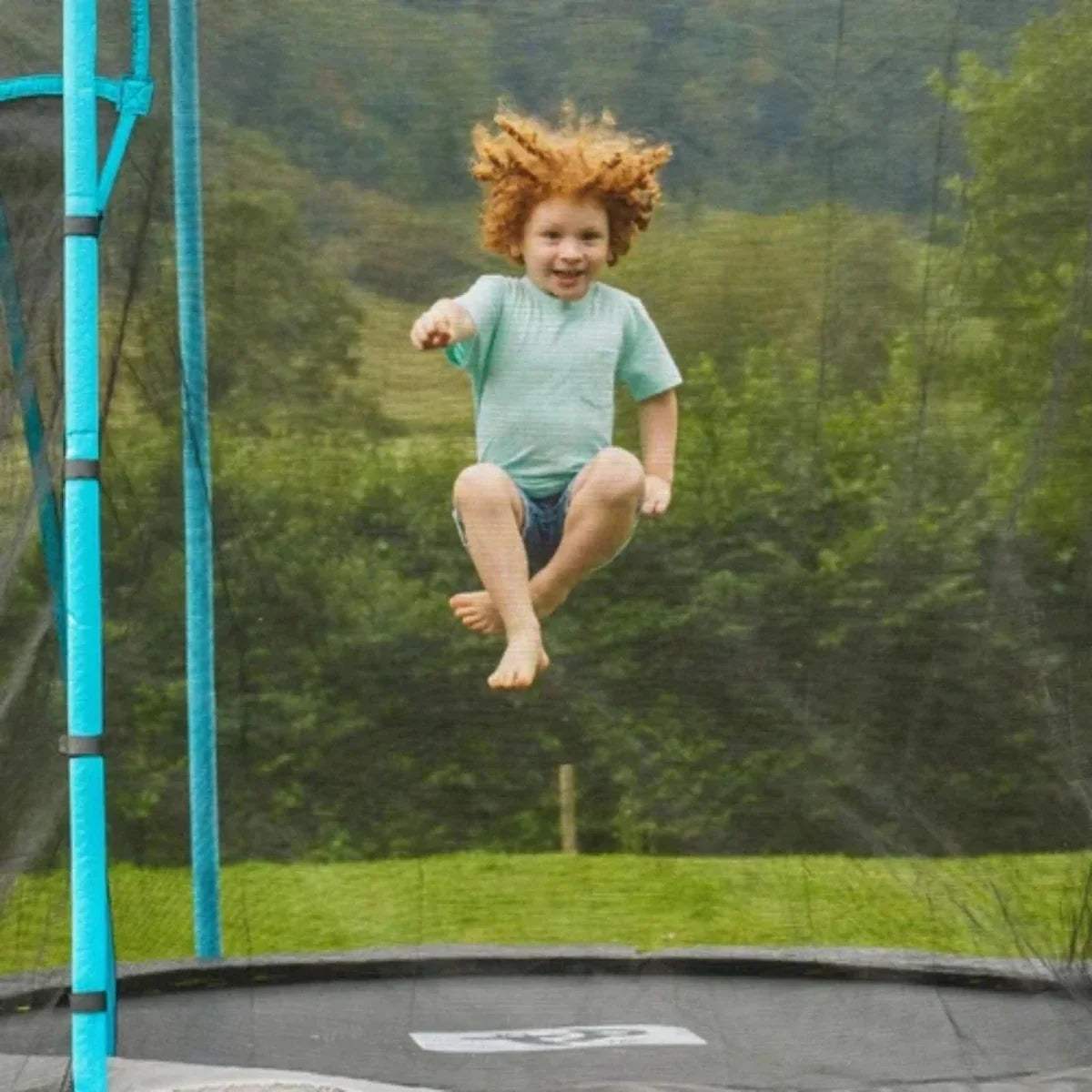 Round trampoline with black safety net and blue poles, view of jumping surface