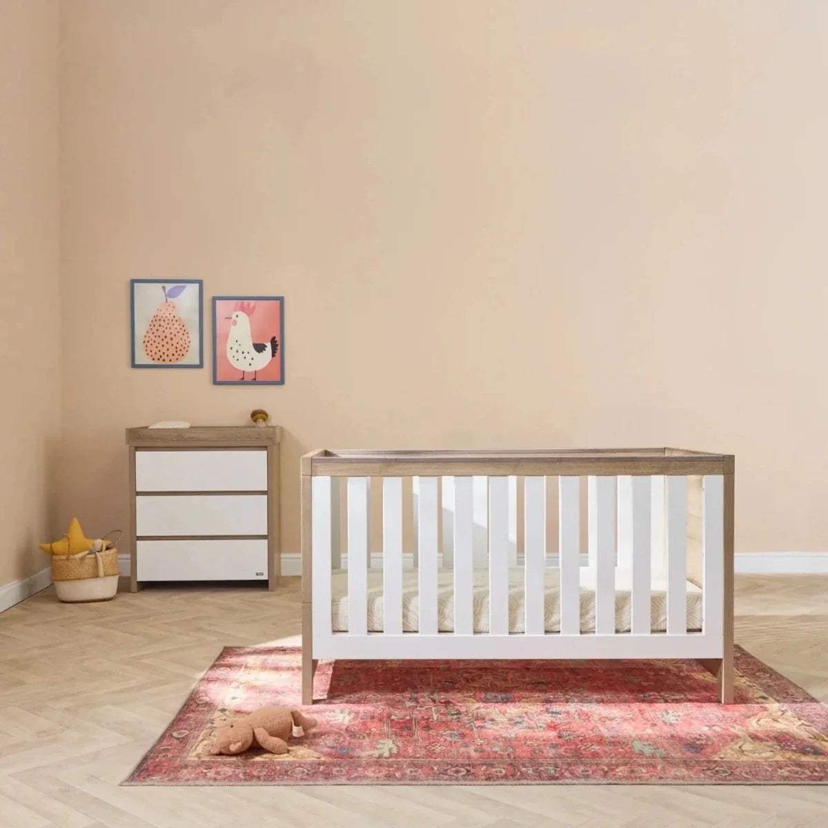 White and oak baby cot bed with matching white dresser in nursery setting