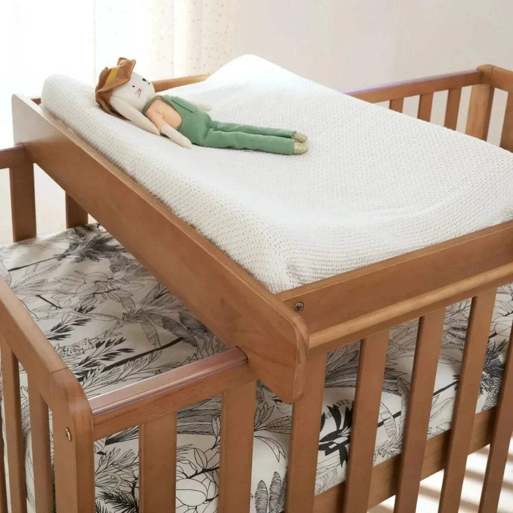 Honey oak cot bed corner with guard rail and woven mattress cover