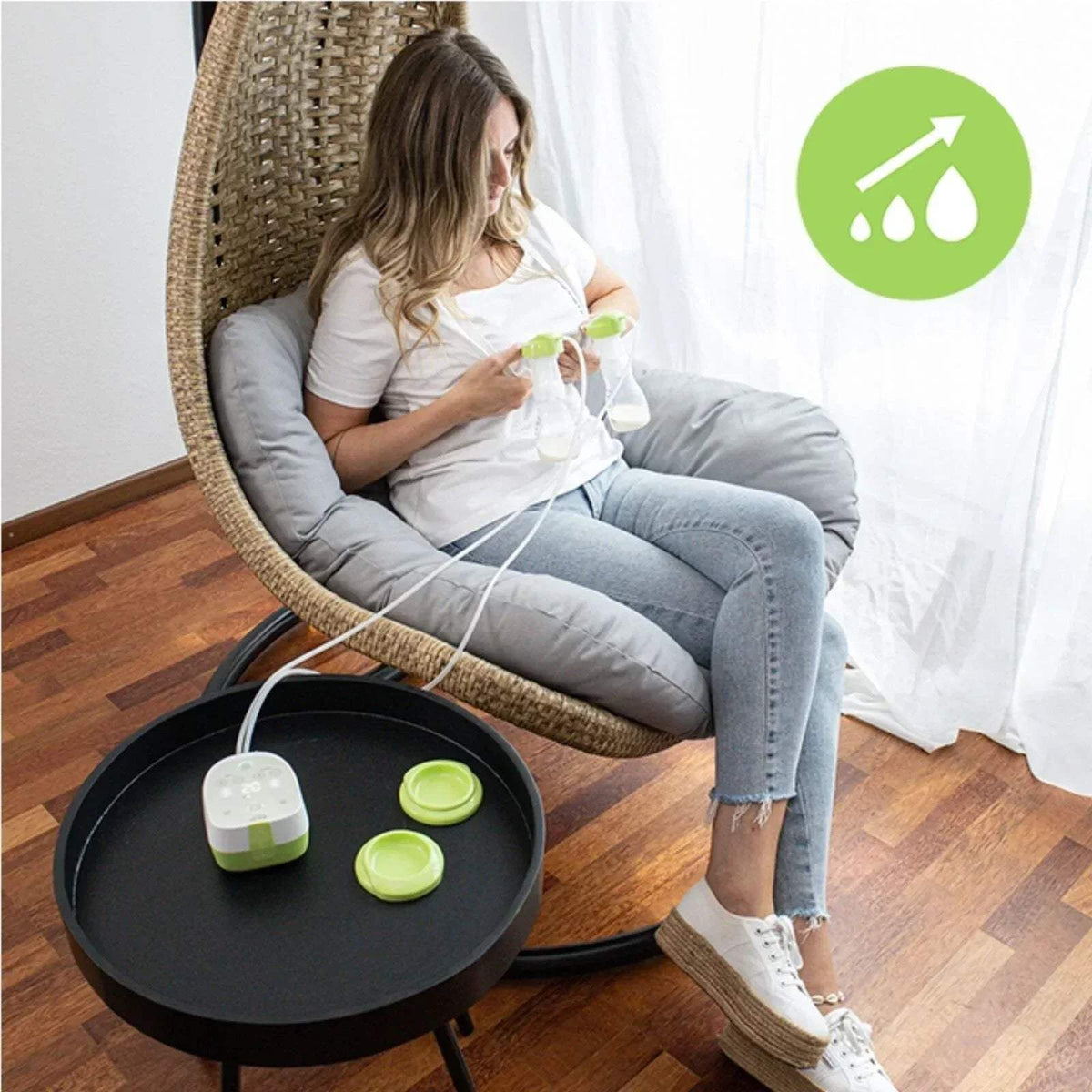 Double electric breast pump in use with collection cups and controller connected to tubing