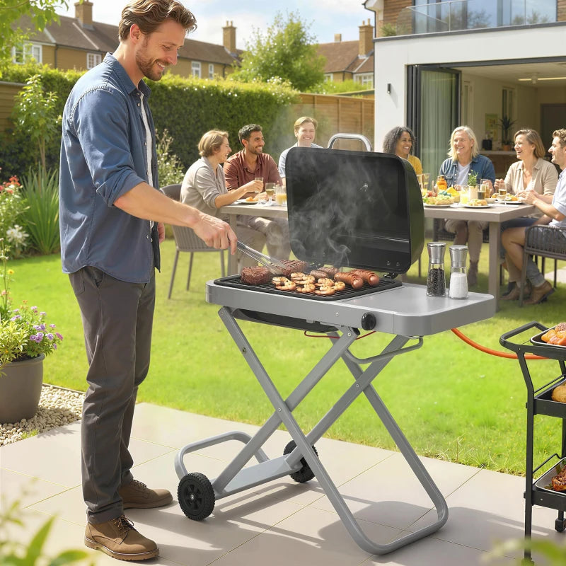 Foldable gas BBQ grill with side table, wheels, open hood cooking food outdoors