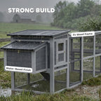 Grey wooden chicken coop with wire mesh run, double doors, and asphalt roof