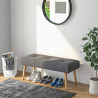 Grey tufted bench ottoman with wooden legs and cushioned top for shoes storage