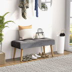 Grey tufted bench ottoman in entryway with wooden legs and cushioned top