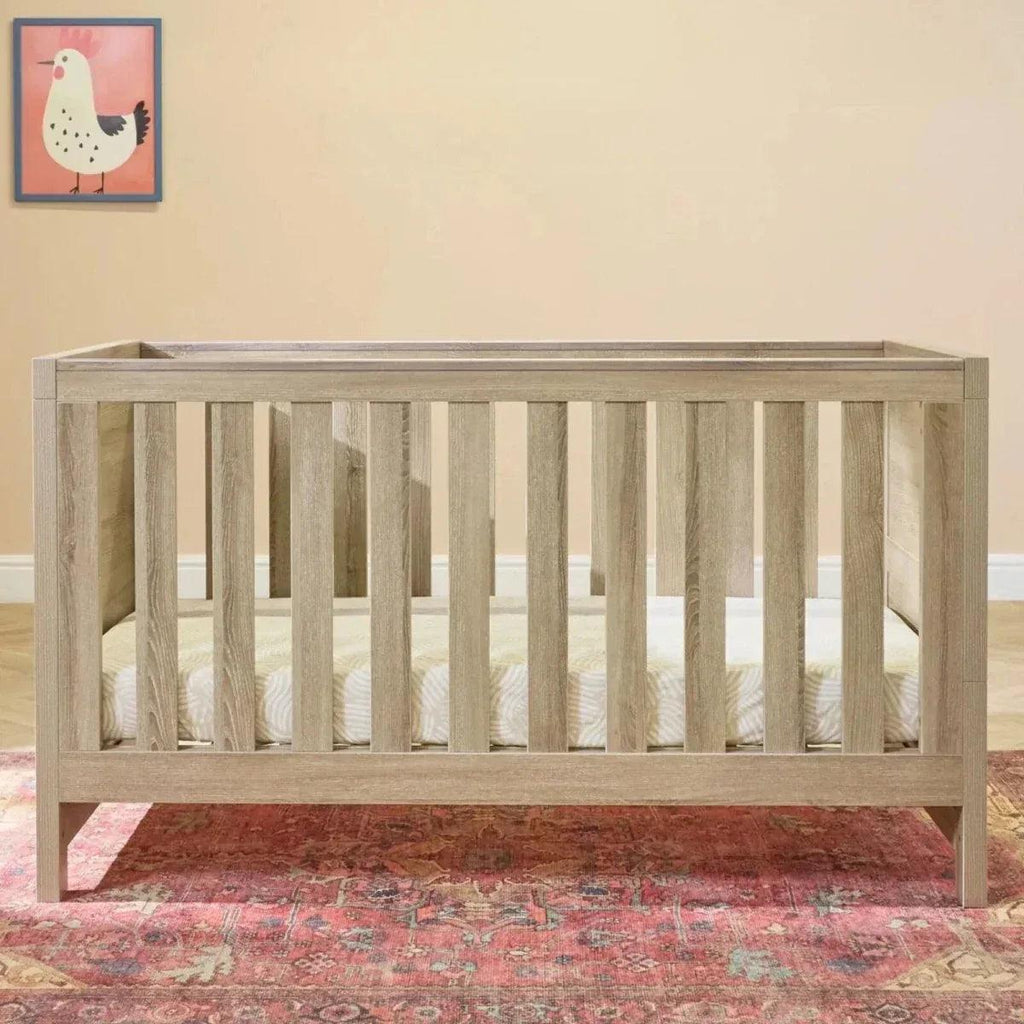 Oak cot bed with vertical slats and open front, light wood frame