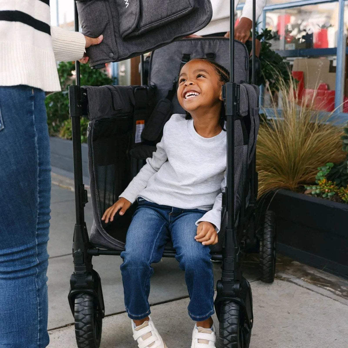 Black stroller wagon seat with child, canopy overhead and side armrests