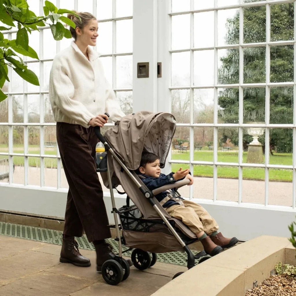 Baby stroller with child seat and patterned canopy, parked near large window