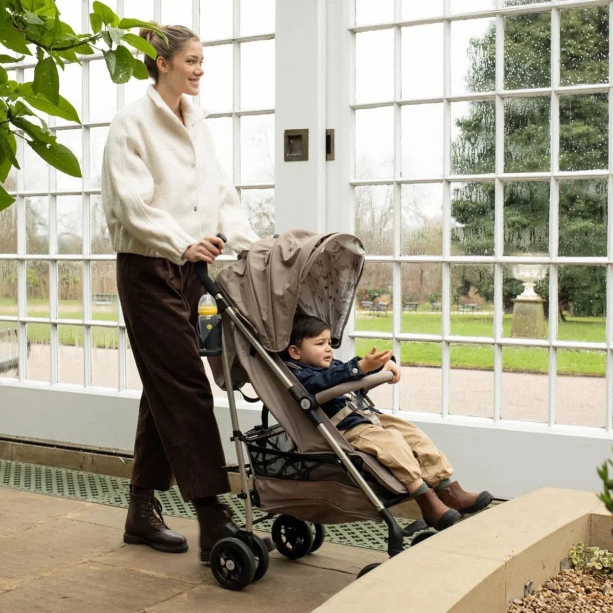 Baby stroller with child seat and patterned canopy, parked near large window
