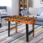 Foosball table with natural wood frame and green playing field in front of sofa