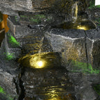 Close-up dark grey rock water fountain with warm white LED light and trickling water