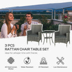 Rattan bistro set with two grey woven chairs and two-tier glass coffee table outdoors