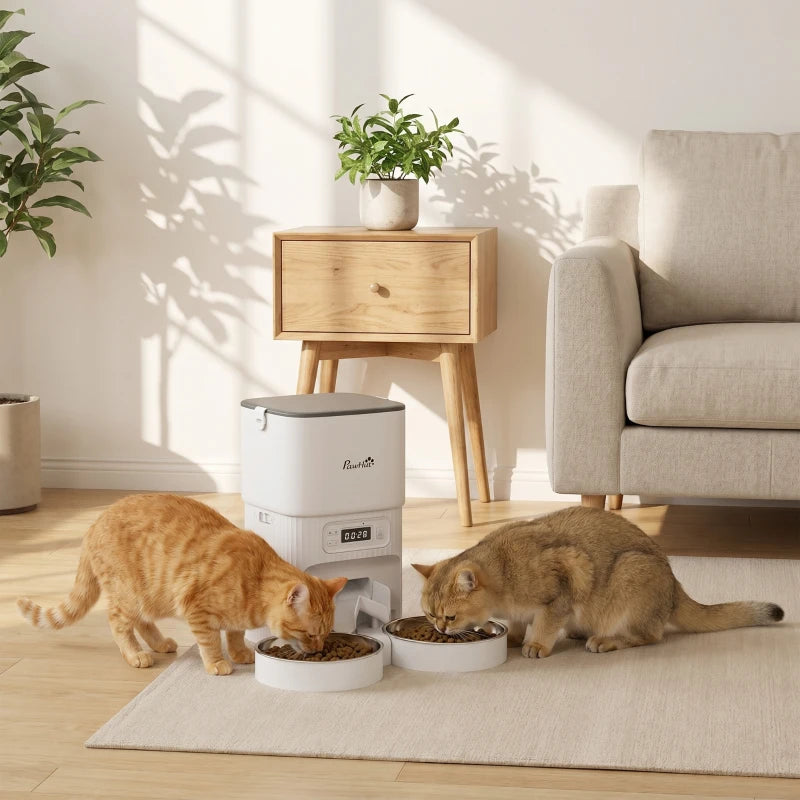 White automatic cat feeder with dual bowls feeding two cats on a floor mat