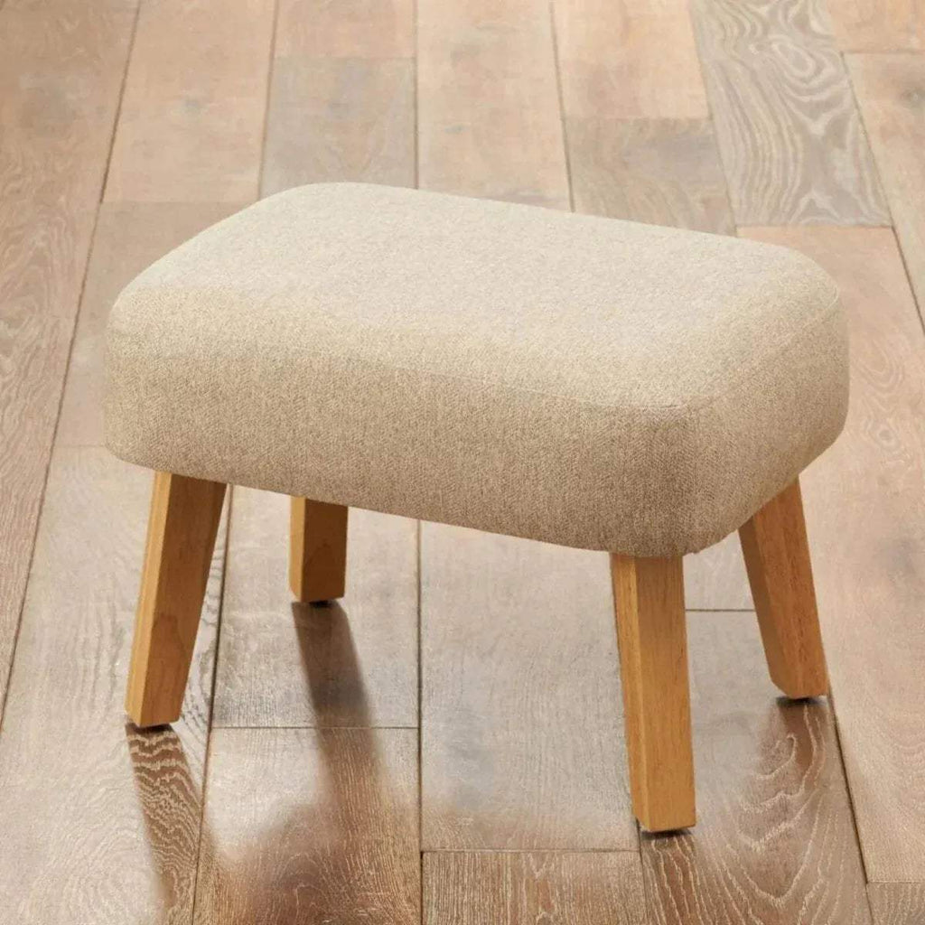 Stone upholstered foot stool with rounded top and light wood legs.
