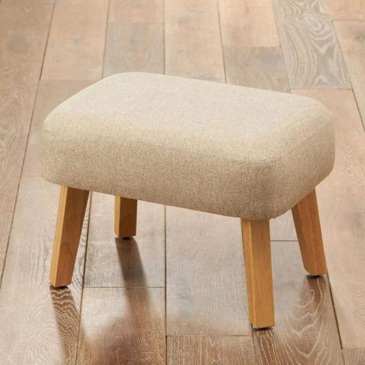 Stone upholstered foot stool with rounded top and light wood legs.