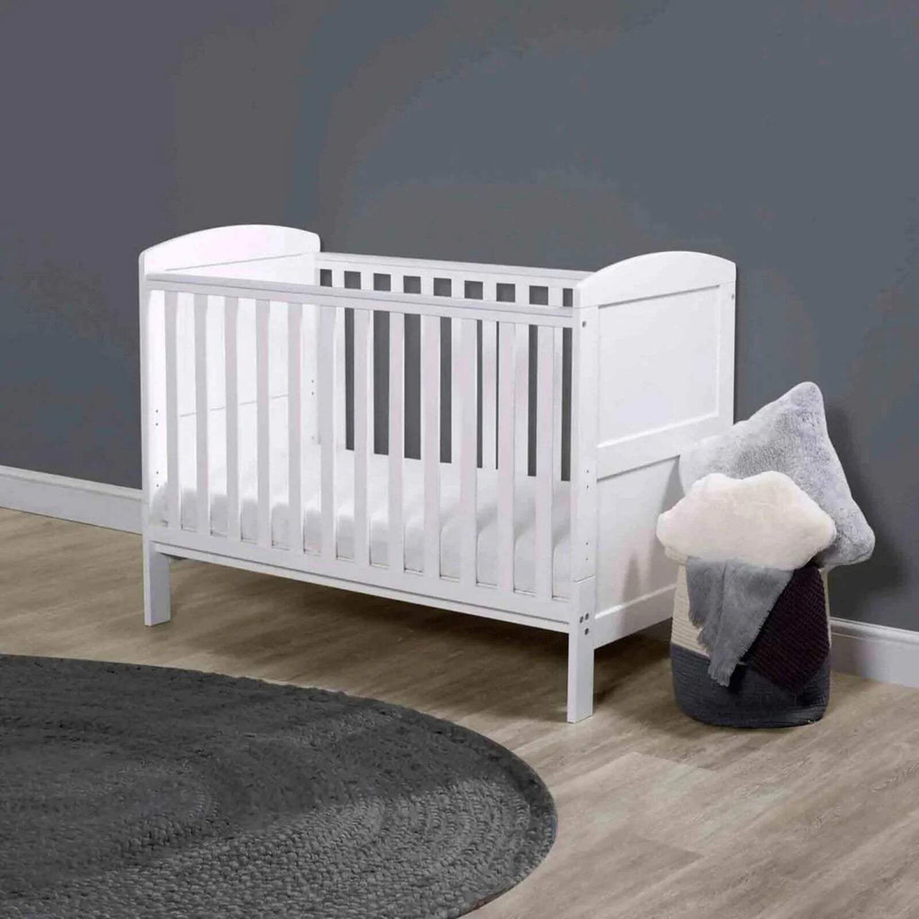 White mini cot bed with mattress installed and vertical safety slat sides