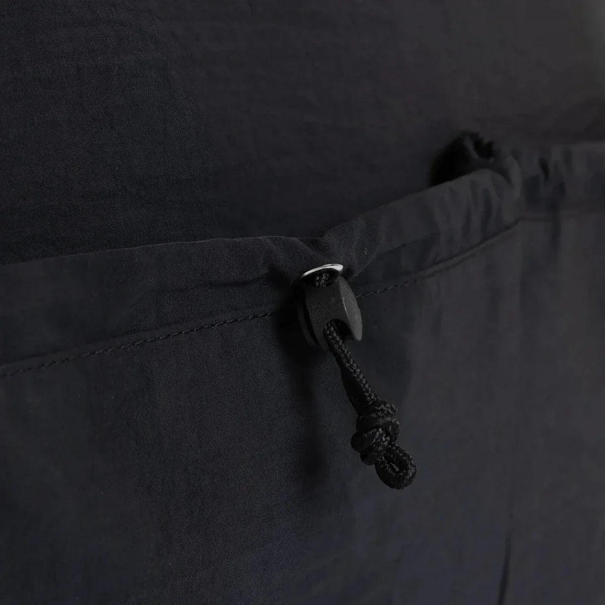 Black quilted shoulder bag close-up of drawstring pull on front panel