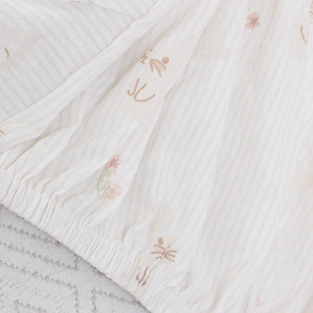 White baby sheet fabric with fine ribbed texture and small pastel floral details