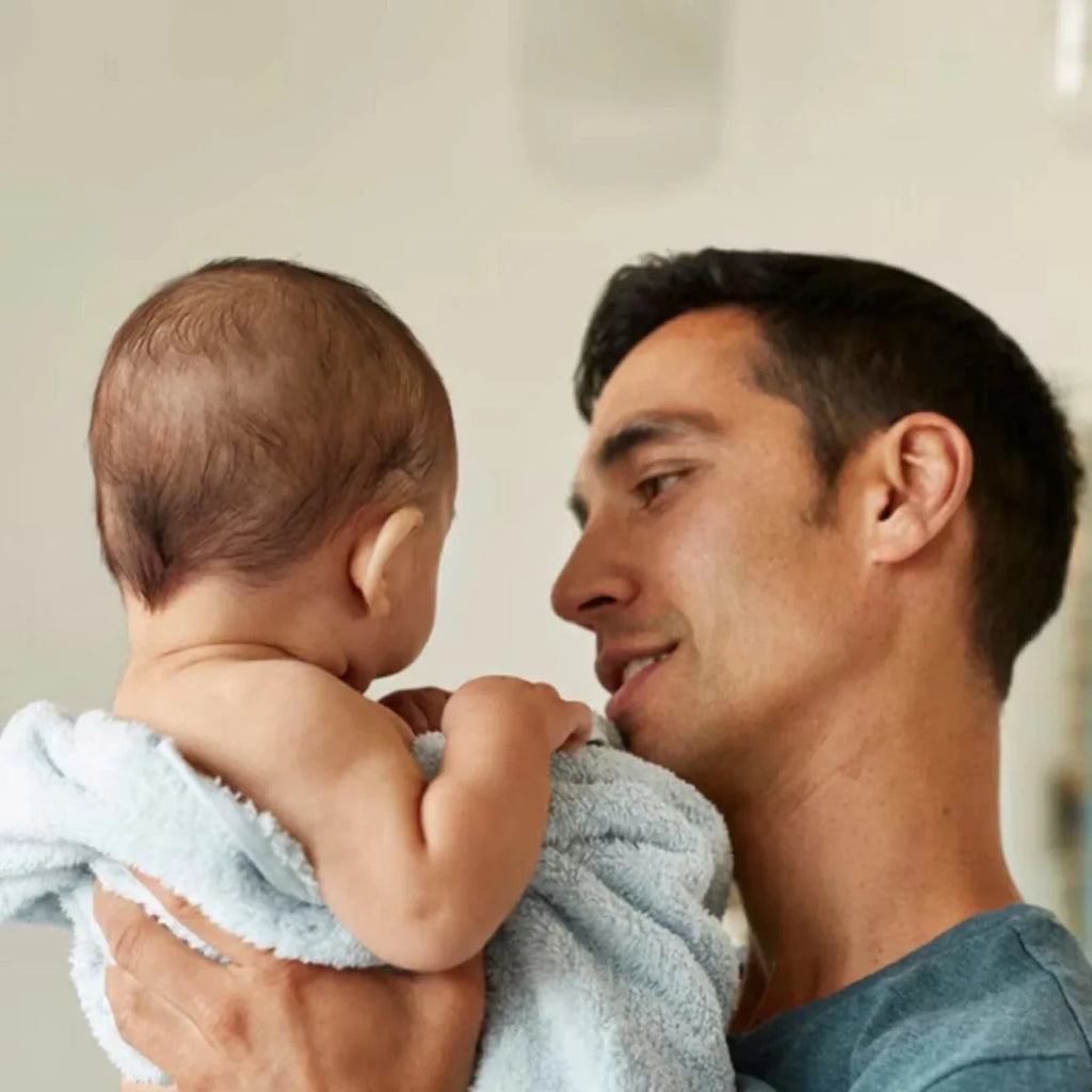 Parent holding baby wrapped in a towel, baby care theme