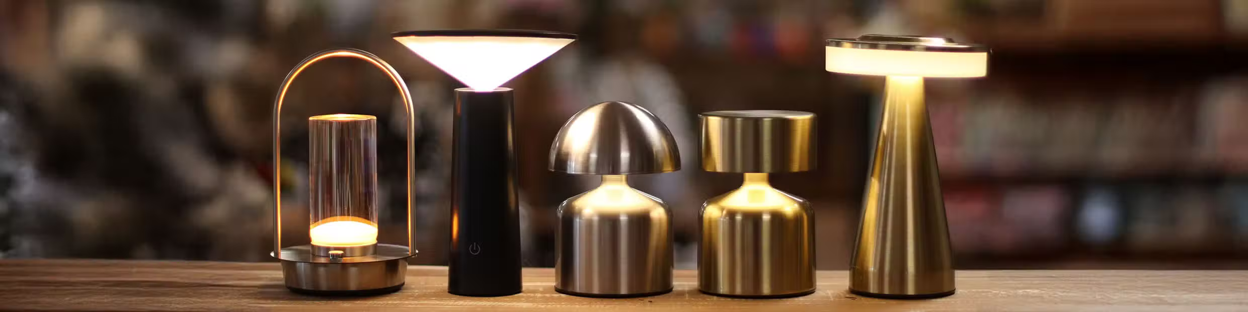 Collection of various table lamps on a wooden surface with a blurred background
