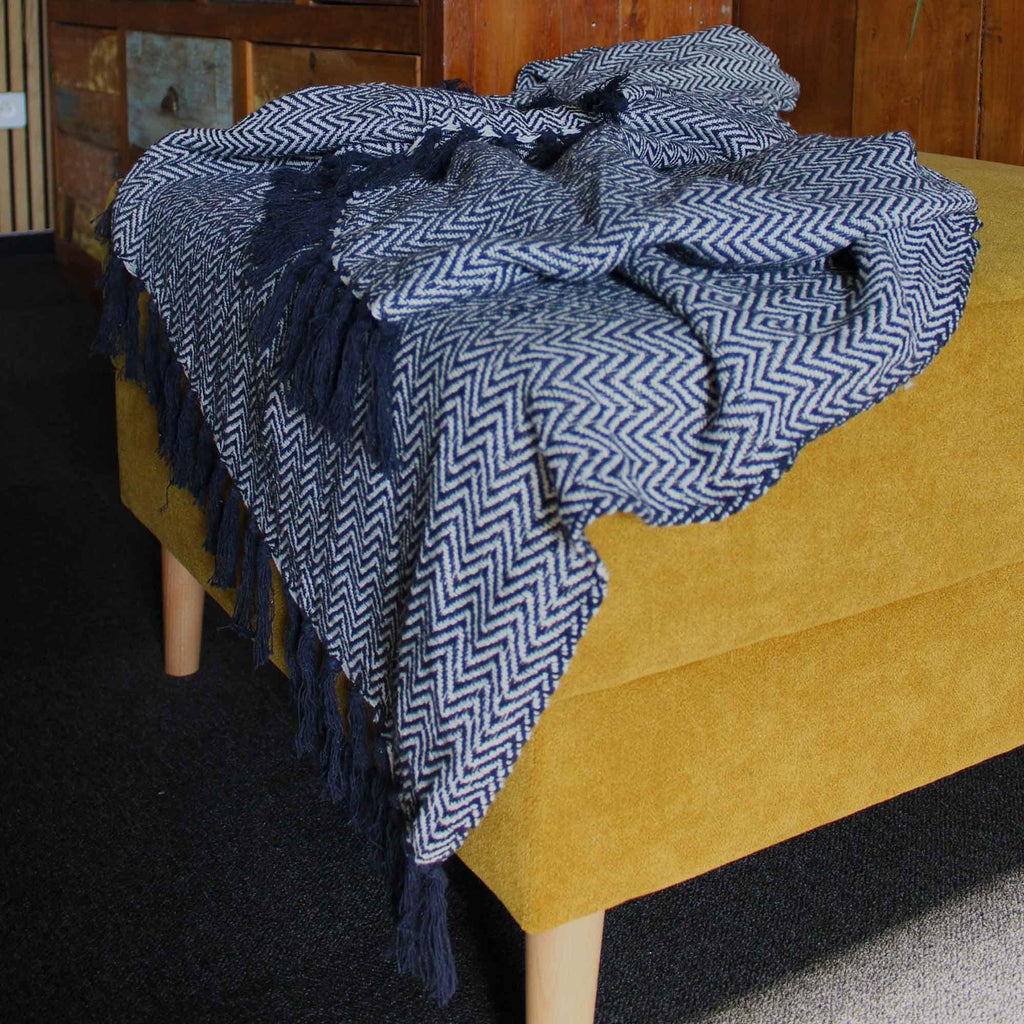 Navy zigzag throw blanket draped over chair with long tassel fringe