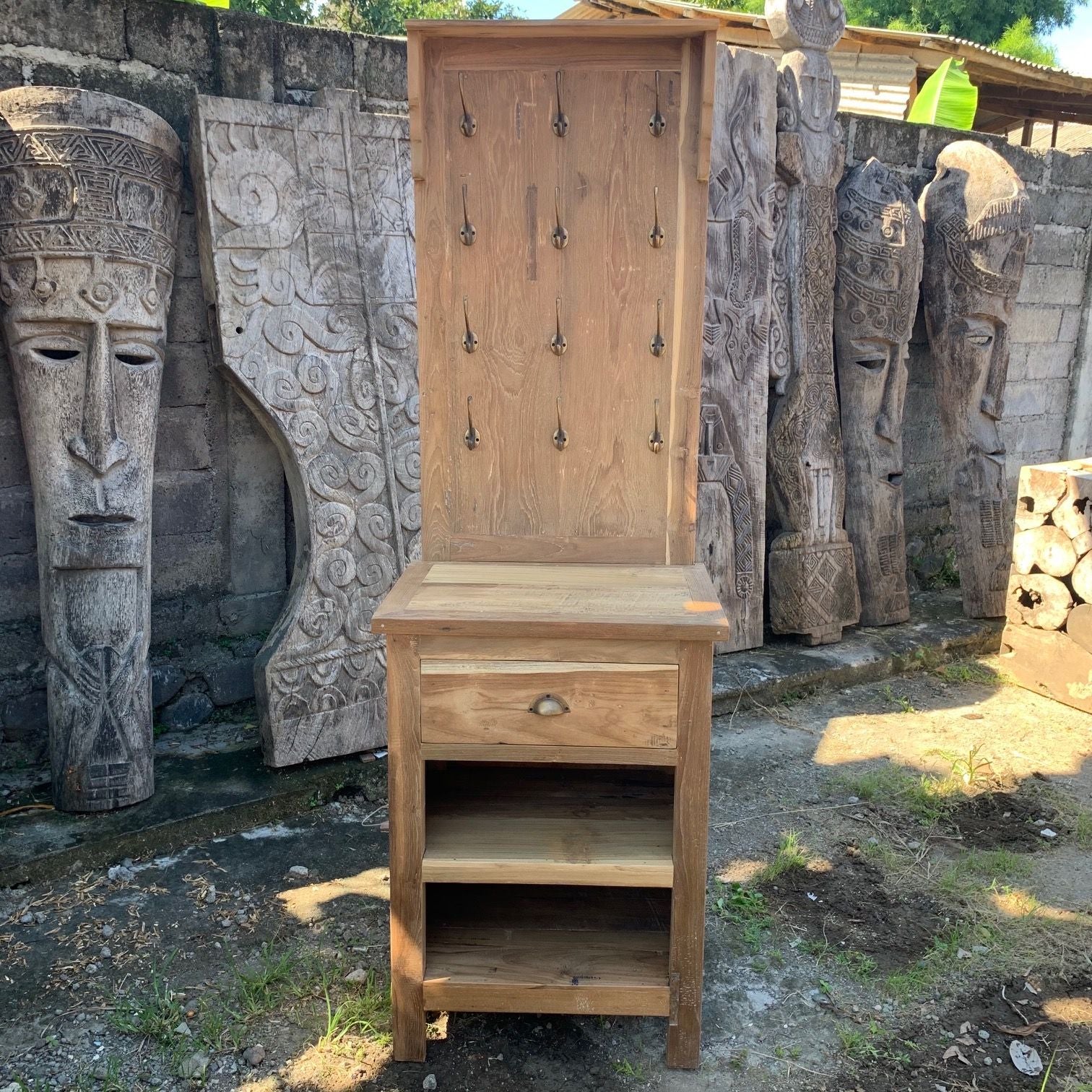 Wooden cabinet with a mirror on top, surrounded by stone sculptures in an outdoor setting.