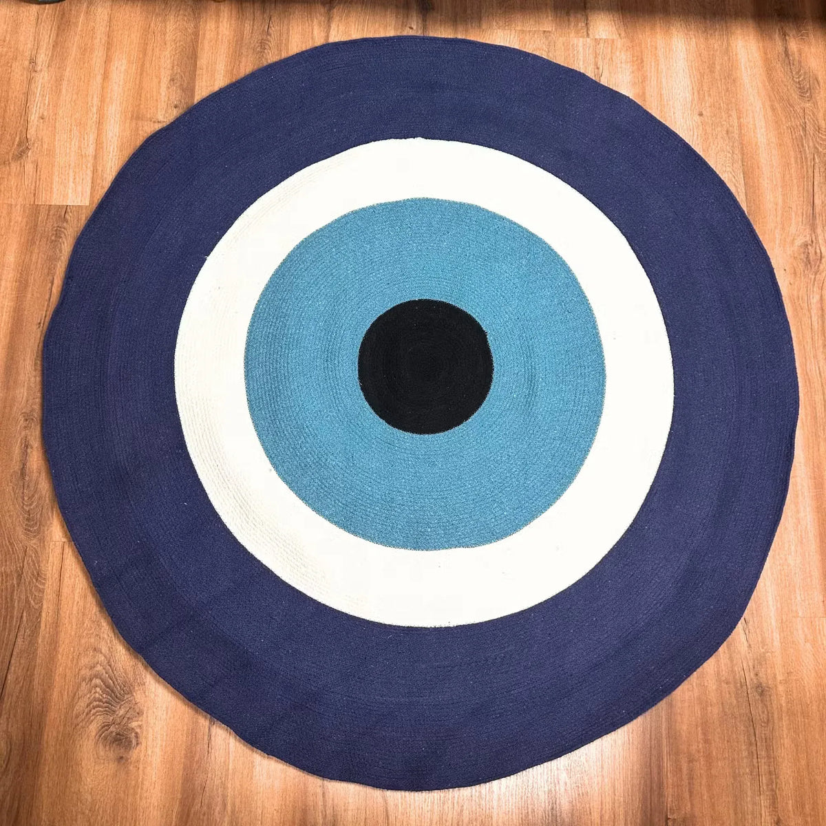 Round cotton rope eye rug with navy, sky blue, white rings and black center.